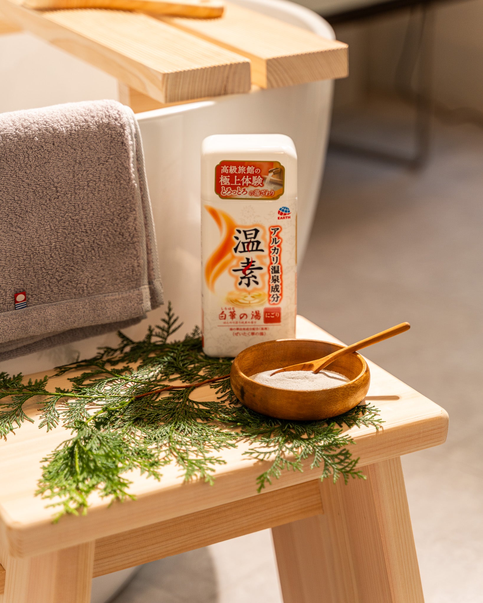 Bottle of Japanese body lotion on a wooden stool with a bowl and green leaves