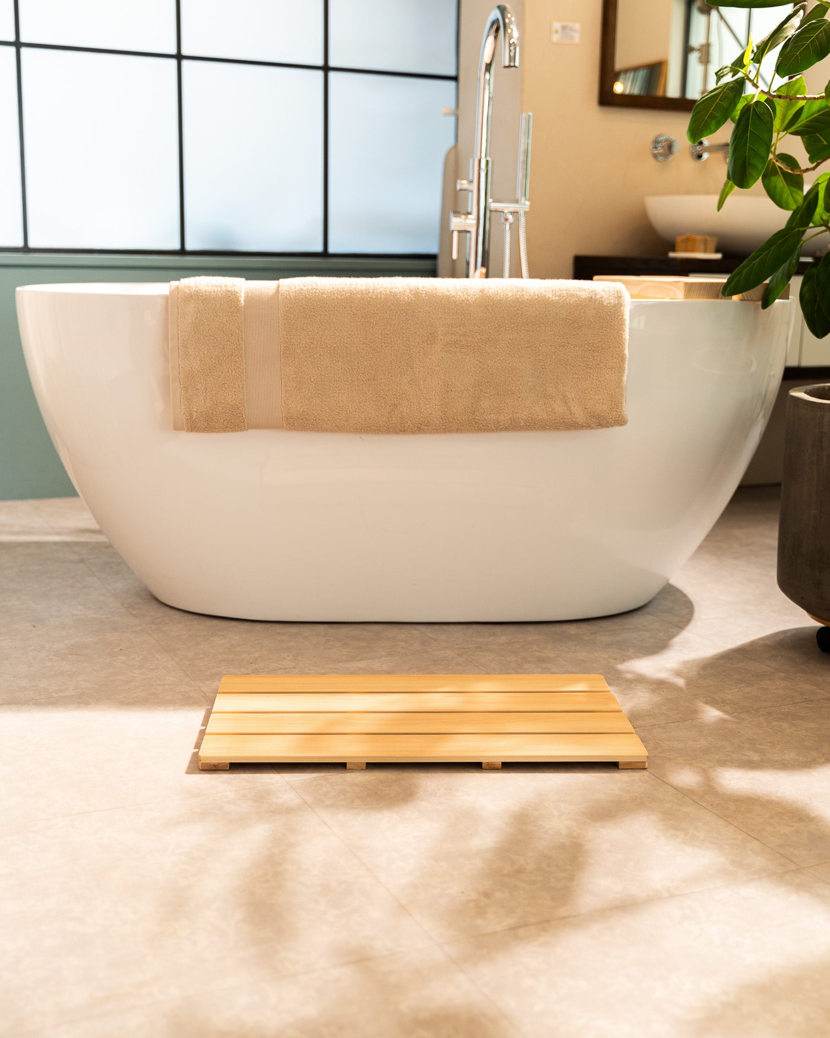 White freestanding bathtub with a towel draped over it in a modern bathroom setting.