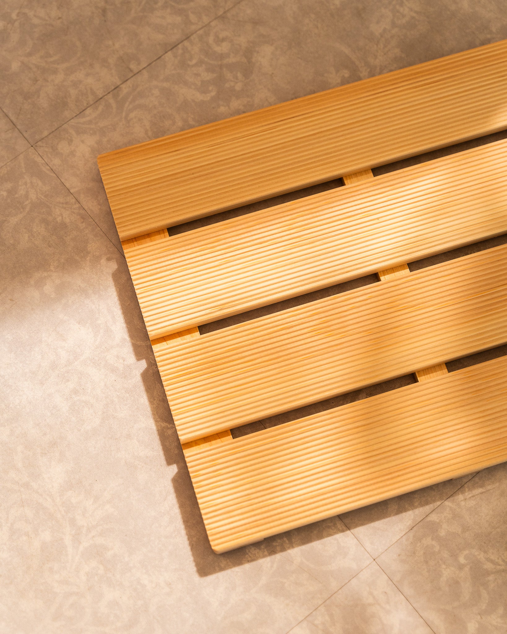 Wooden bath mat on a tiled bathroom floor