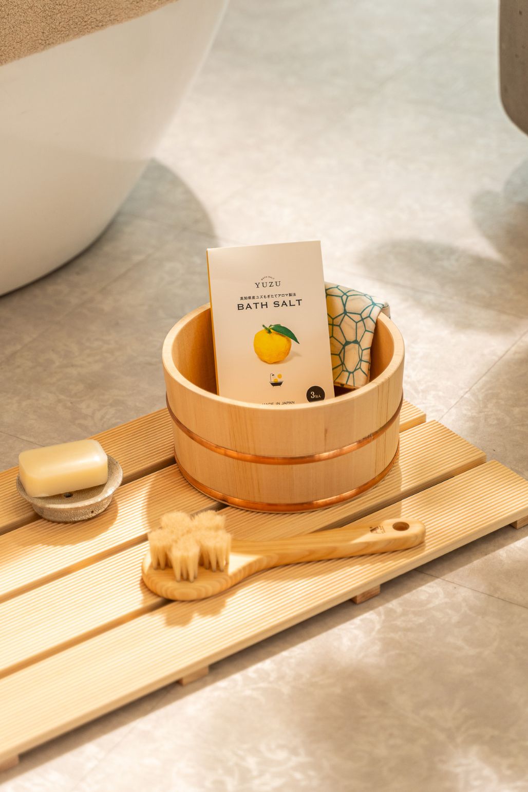 Bath accesories set with Yuzu bath salt, sakura brush and soap on a wooden bath hinoki mat