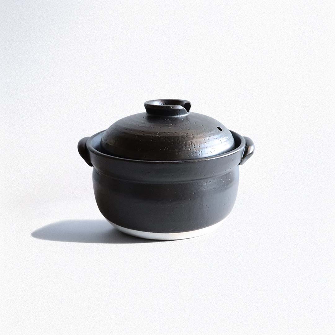 Black ceramic pot with lid on a white background