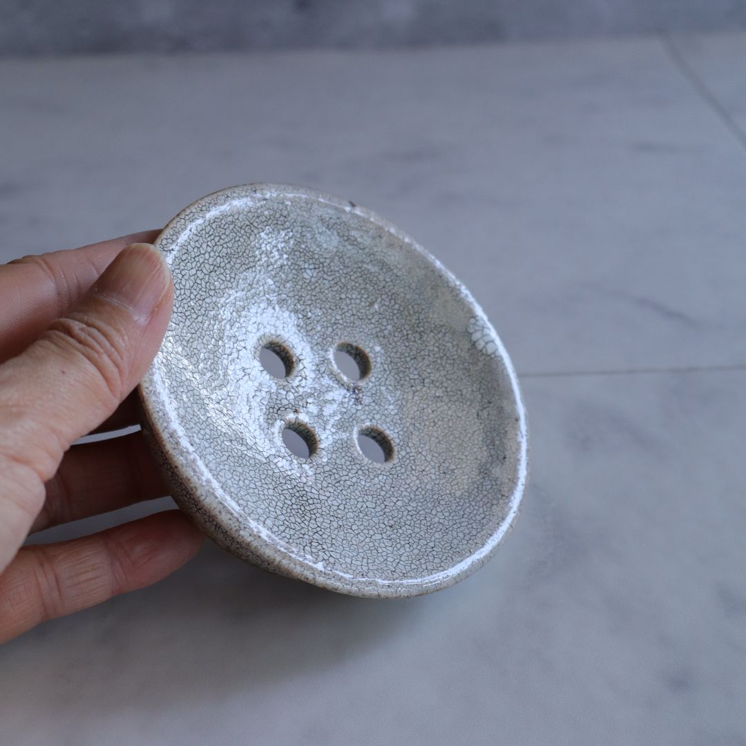 A person holding the handmade ceramic soap dish, highlighting its compact size and fine kairagi glaze pattern