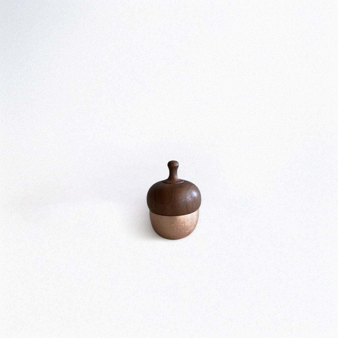 A small acorn-shaped healing bell with a rose gold base and a wooden top.