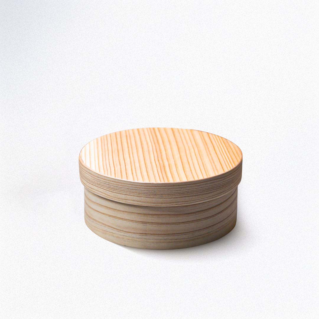 A round Japanese cedar wood lunch bento box on a white background.
