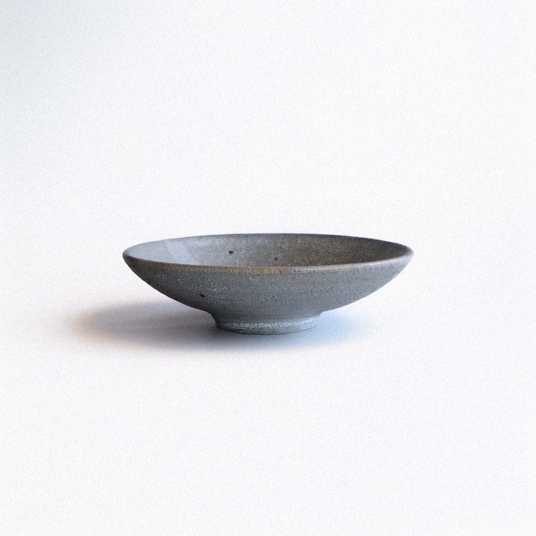 Side view of the handmade ceramic plate, showing its gently flared rim and slightly elevated foot.