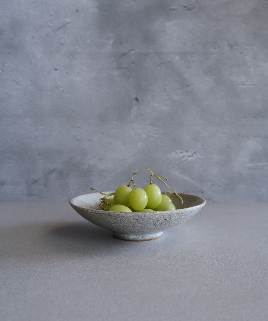 The handmade Japanese plate being used to serve fresh green grapes, highlighting its function and aesthetic charm.