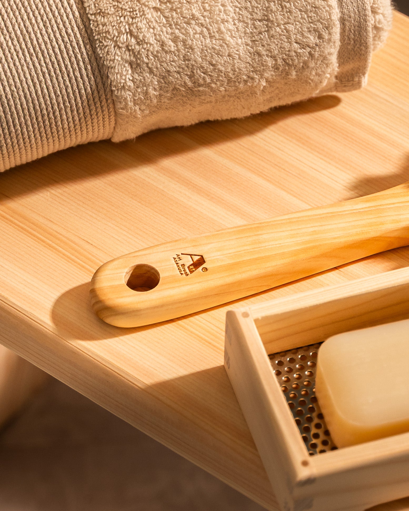 Wooden brush and soap on a wooden tray with a towel in the background