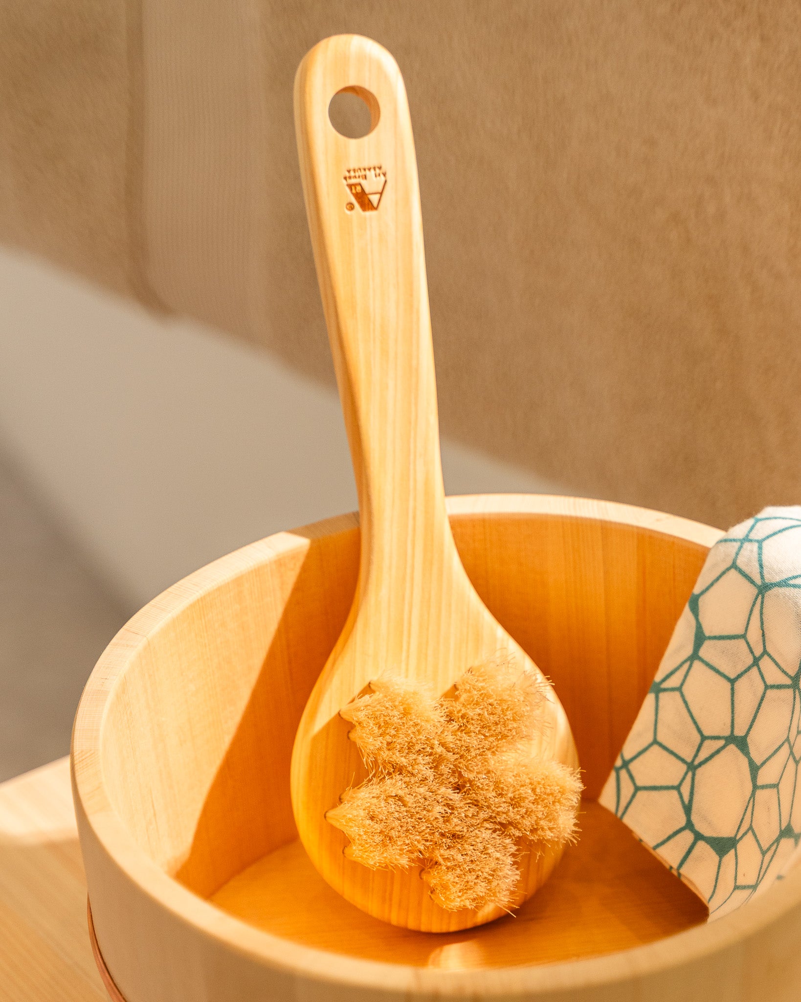 Wooden scrub brush with natural bristles in a wooden bowl on a neutral background