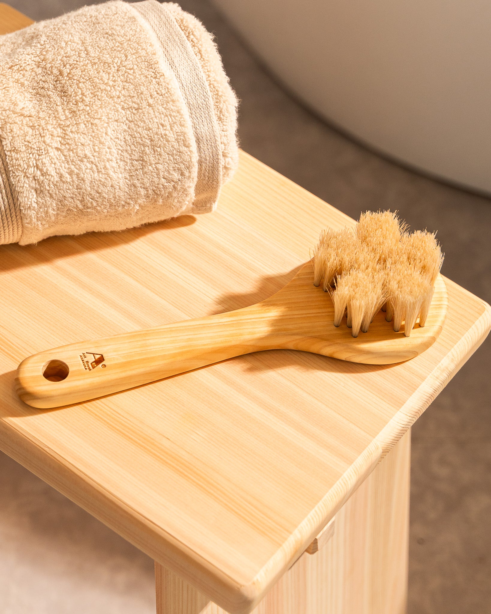 Wooden brush with bristles on a wooden surface next to a towel