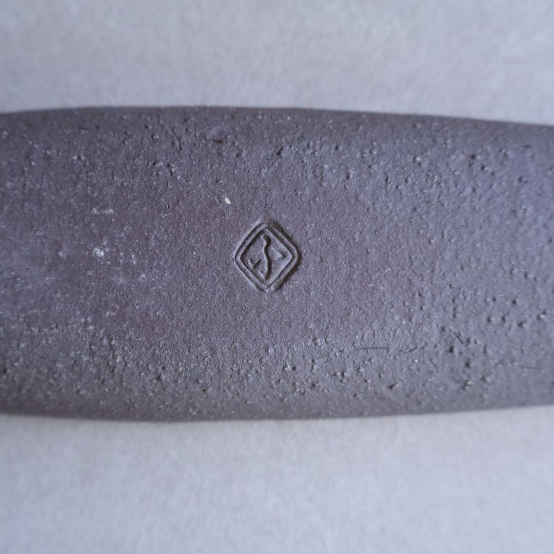 Textured gray object with a logo on a light gray background