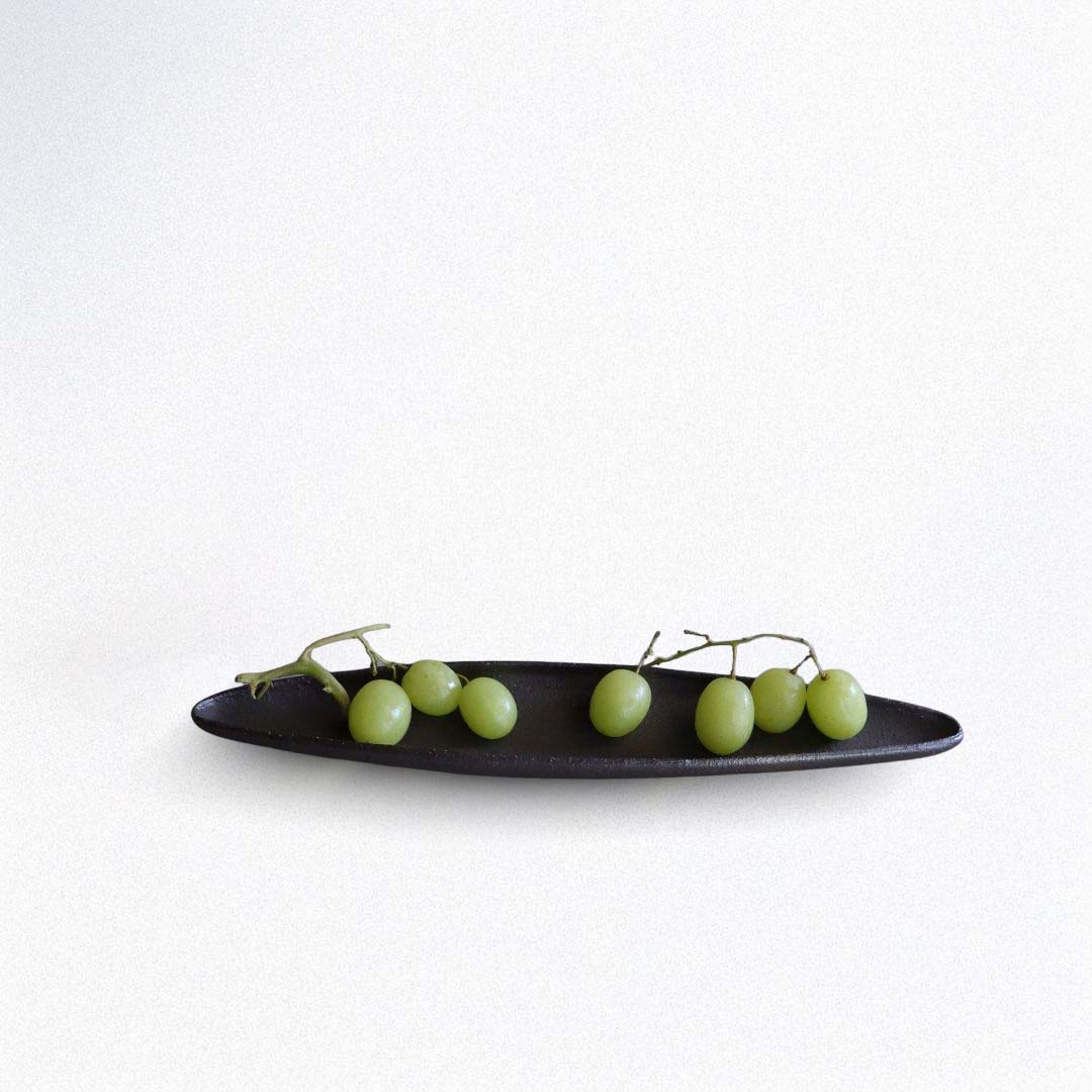 Green grapes on a black plate against a white background