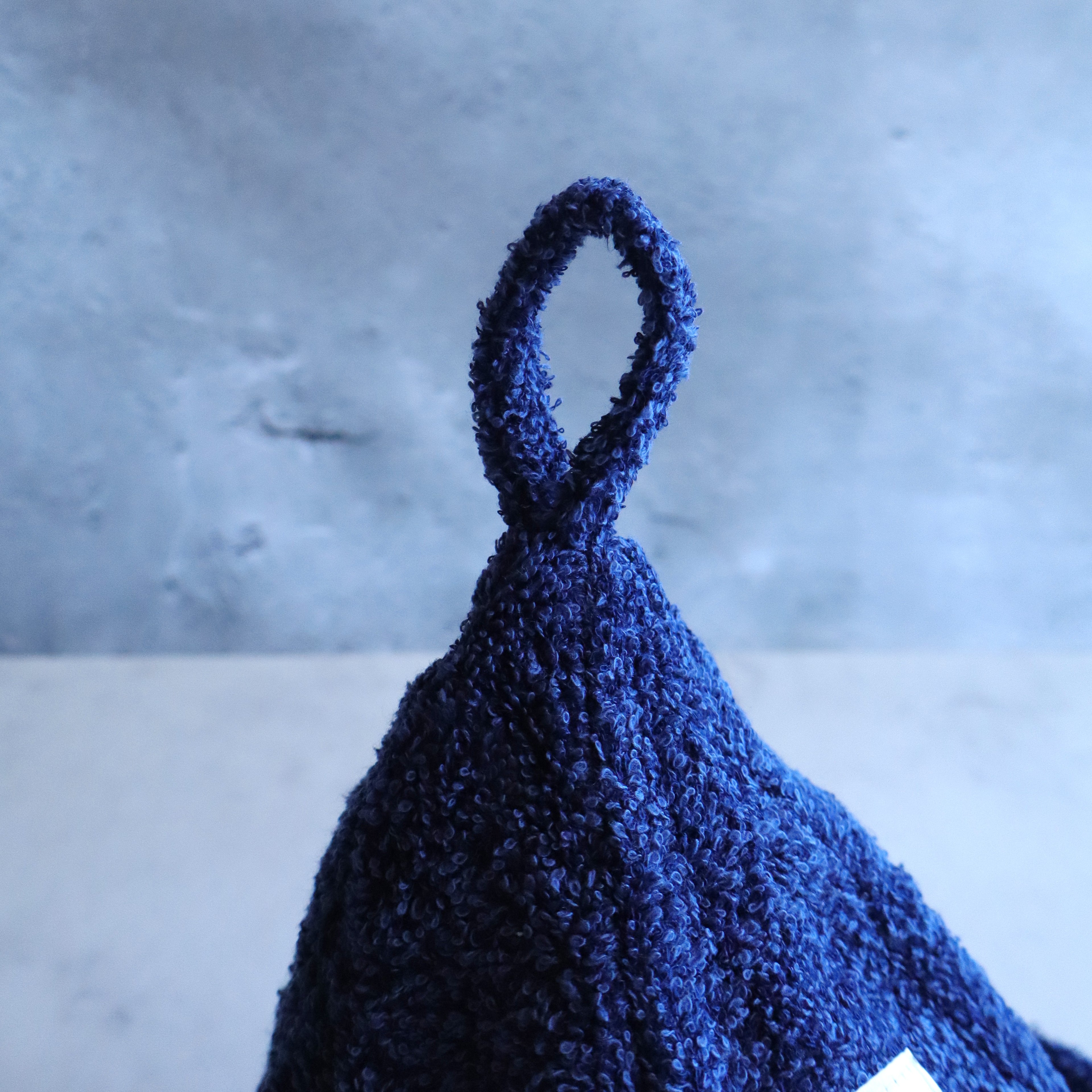 Close-up of the navy sauna hat’s fabric loop for easy hanging; plush terry texture visible.