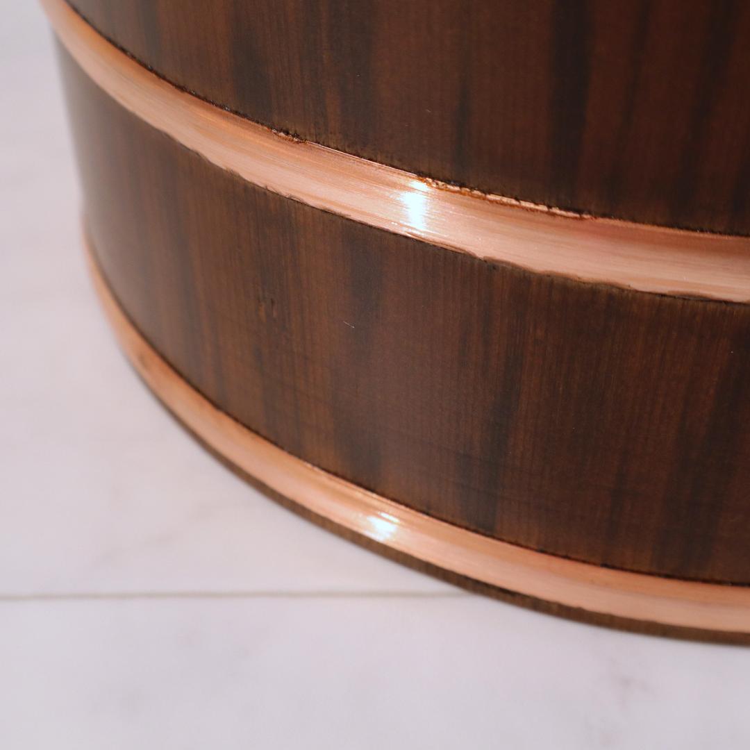Close-up of a wooden barrel with a copper rim on a white background