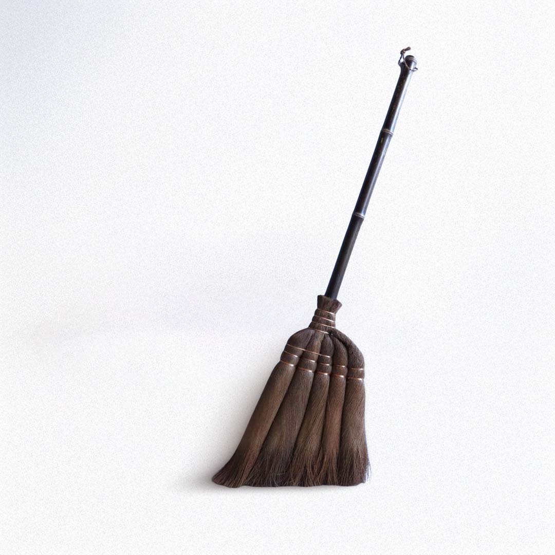 Traditional japanese broom with a black handle on a white background