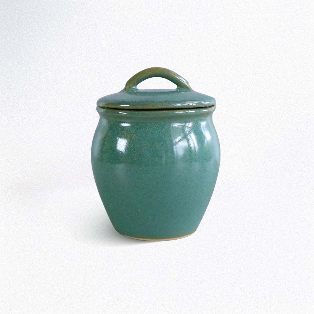 Teal ceramic jar with a lid on a white background