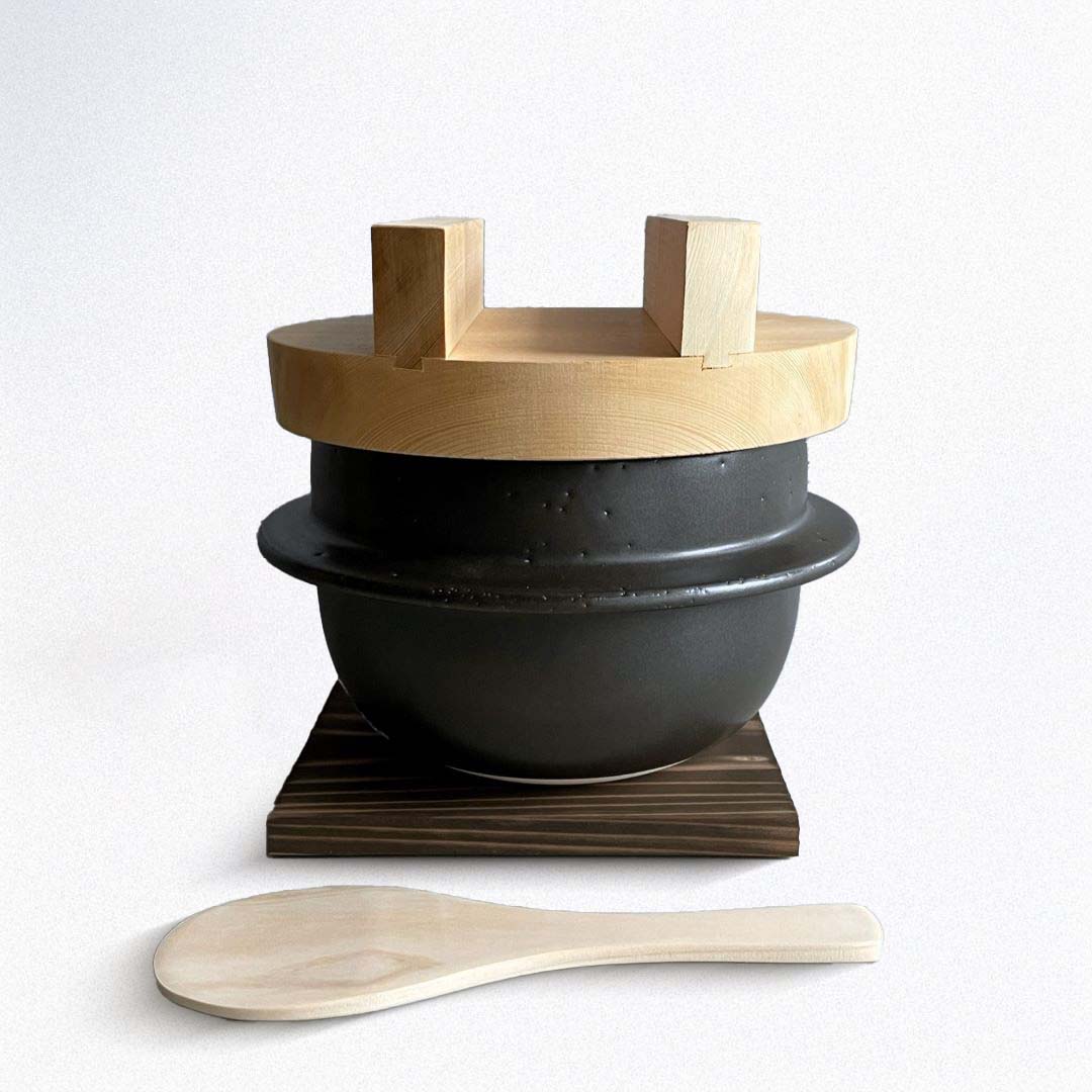 A Japanese handmade rice cooker with a wooden lid and a wooden spatula.