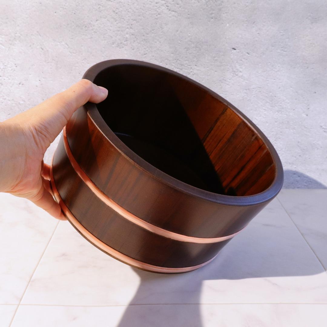Hand holding a wooden basket against a light background