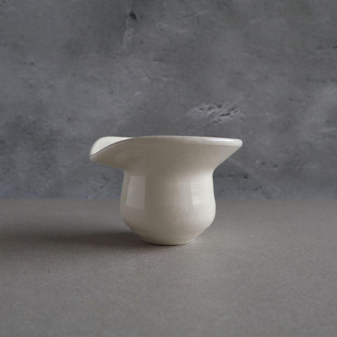 White ceramic pitcher on a gray surface with a gray background