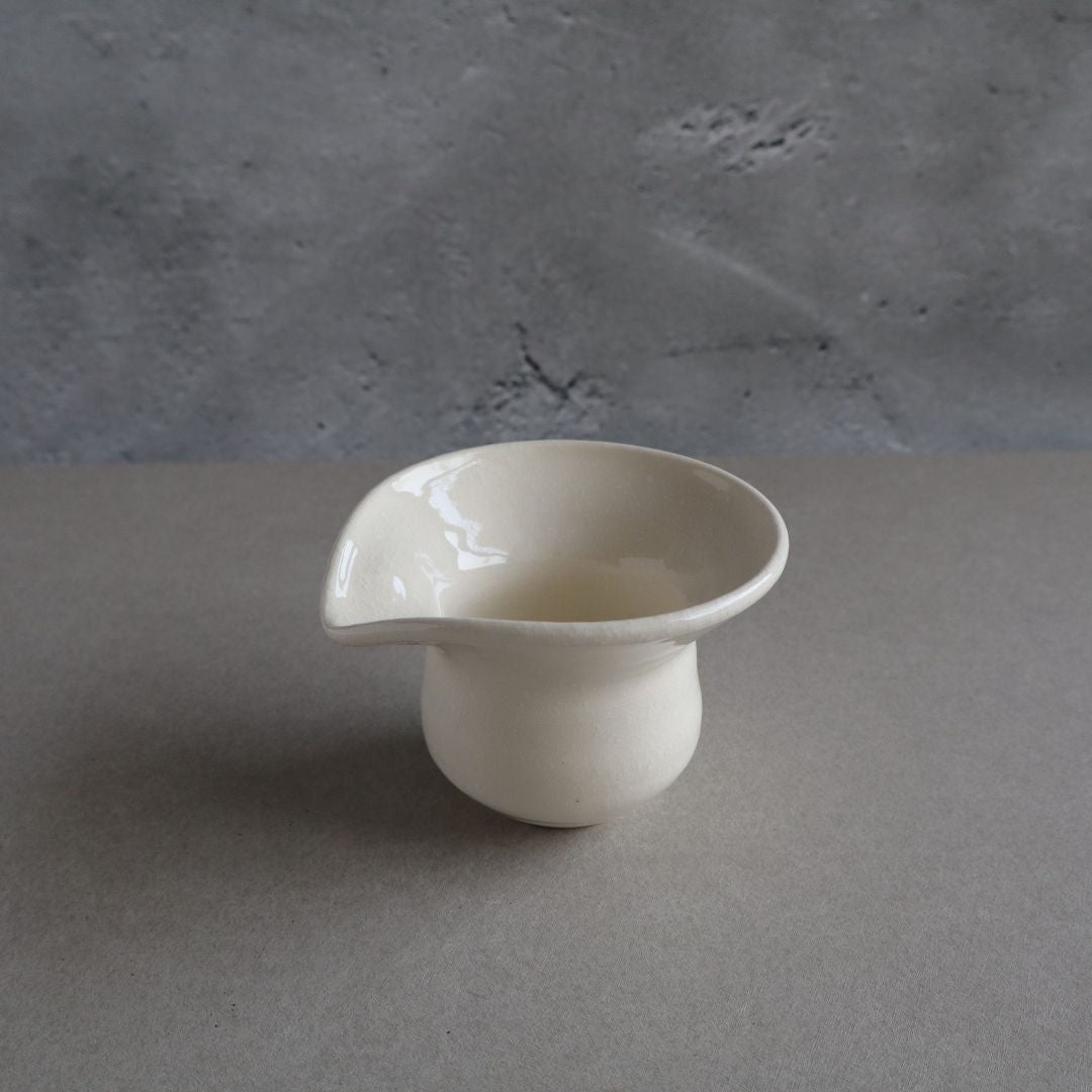 White ceramic cup on a gray surface with a gray background