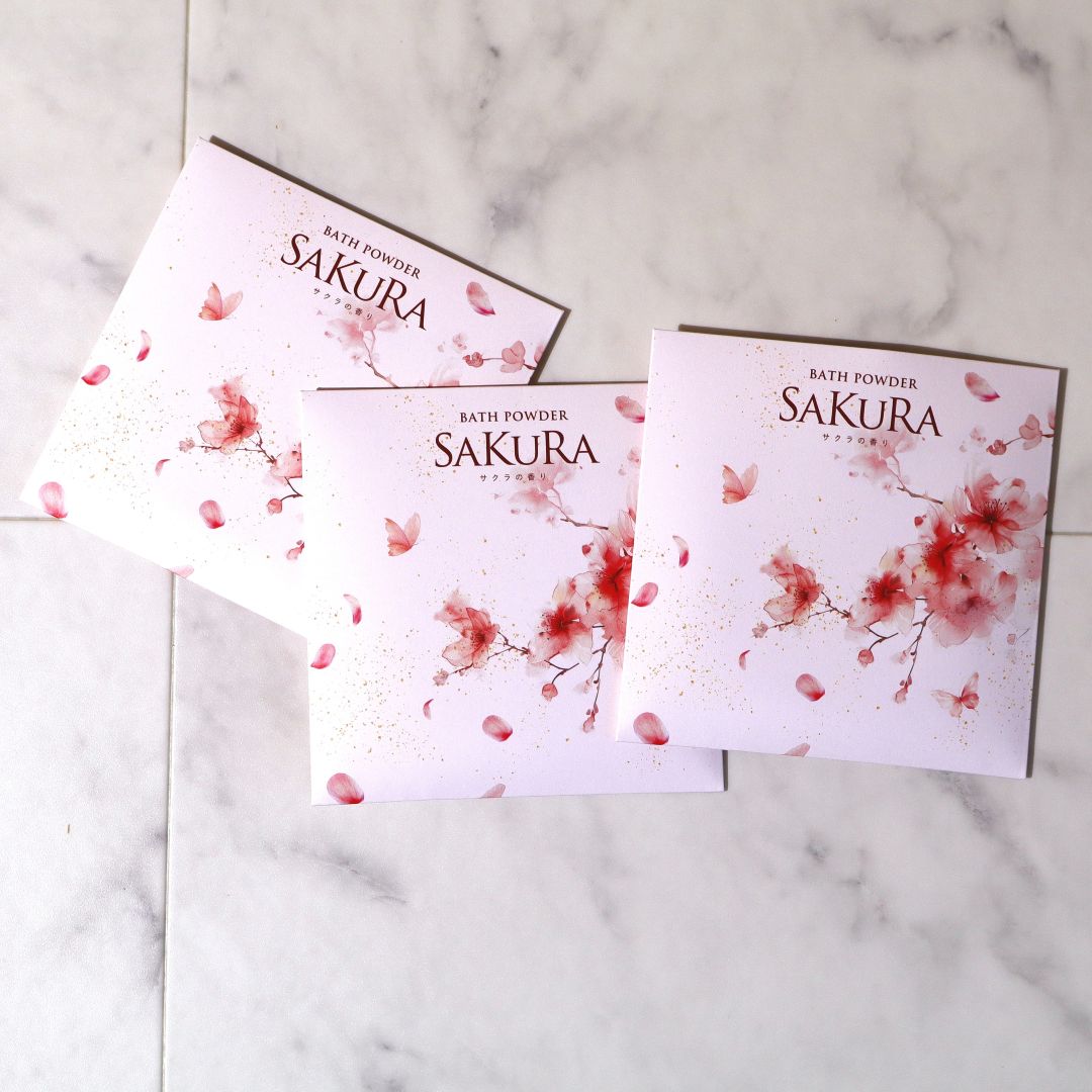 Three packages of Sakura bath powder on a marble surface