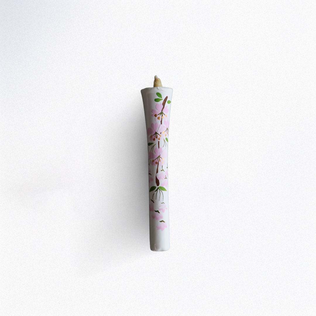 Candle in a decorative paper holder with floral design on a white background