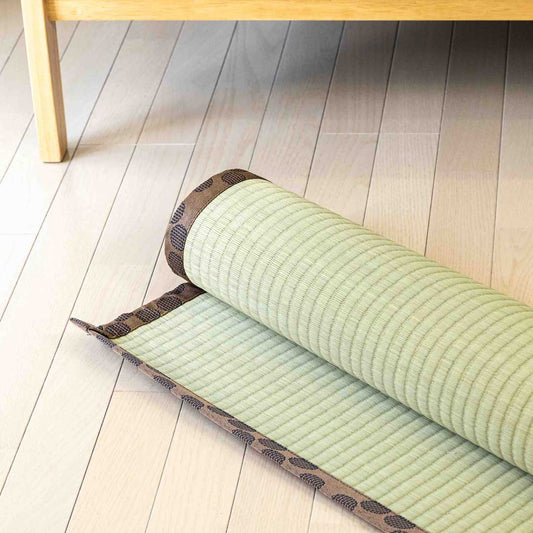 brown tatami Ando rolled on wooden floor in front of a sofa