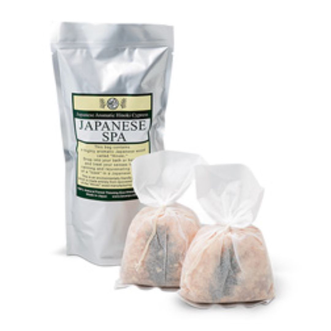 Two white spa aroma bags filled with pink salts and branches of Hinoki wood, sealed with elegant bows, accompanied by a silver package labeled 'JAPANESE SPA'.