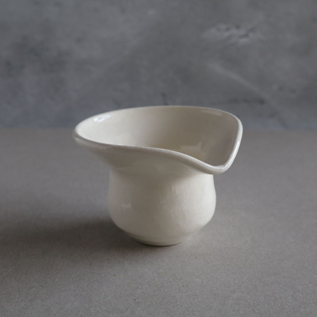 White ceramic cup on a gray surface with a gray background