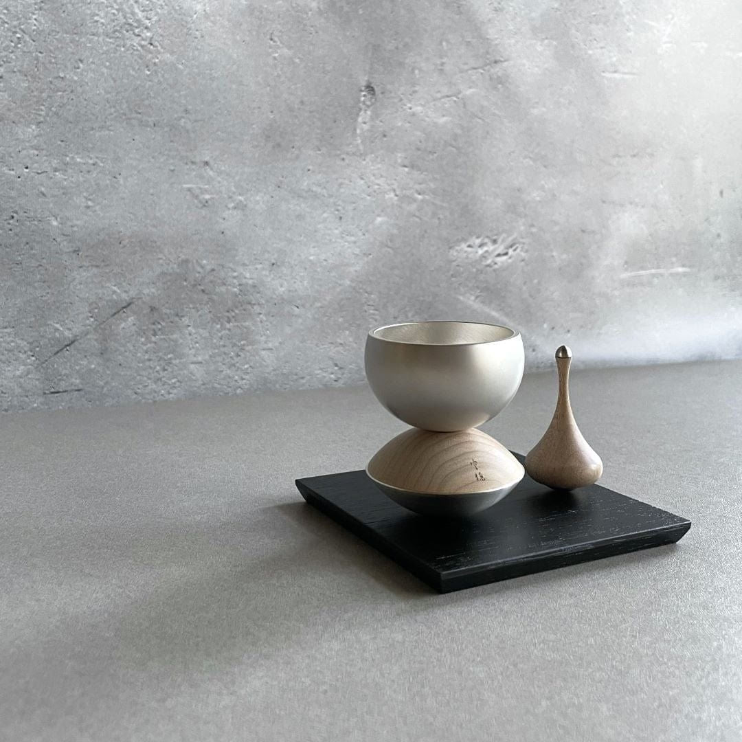 Healing bell made of wood and brass next to the sticker made of wood on a black wooden block