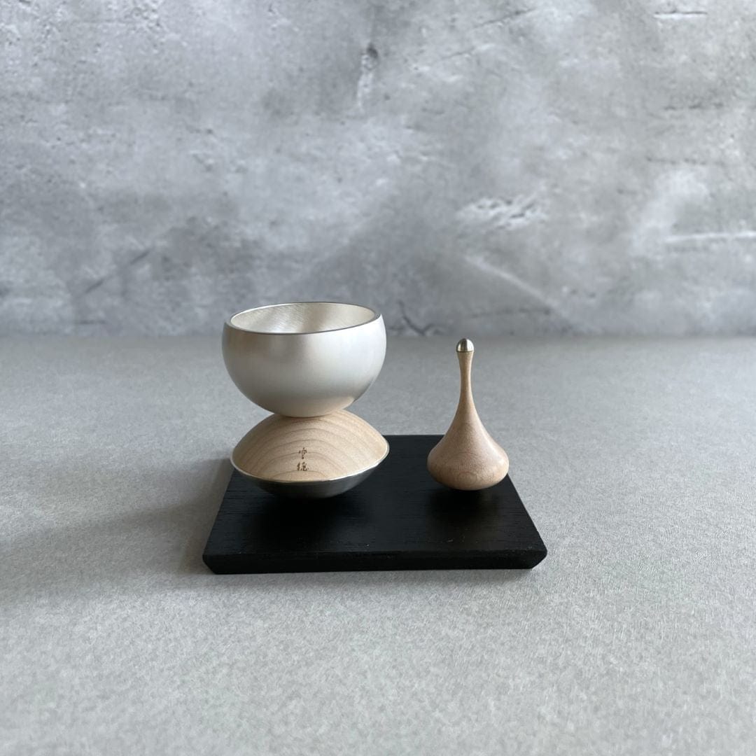 Healing bell made of wood and brass next to the sticker made of wood on a black wooden block