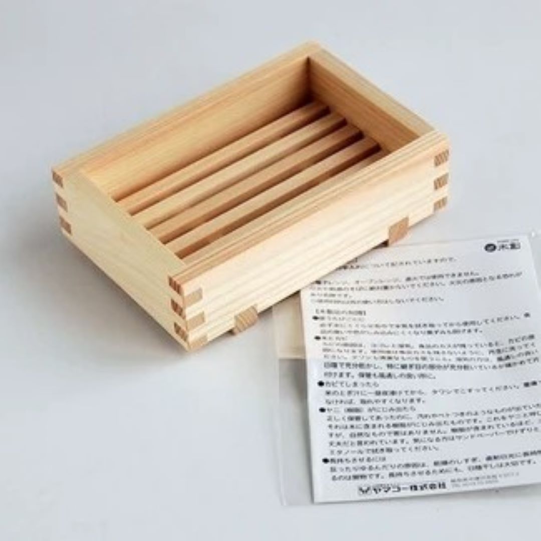 A wooden soap stand on a white floor with a notice next to it