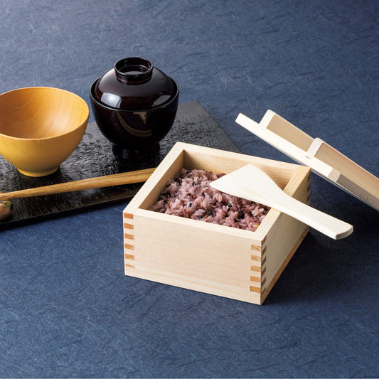 Brown wooden bowl and lacquered bowl side by side, next to a wooden rice container with rice inside, all placed on a blue surface.