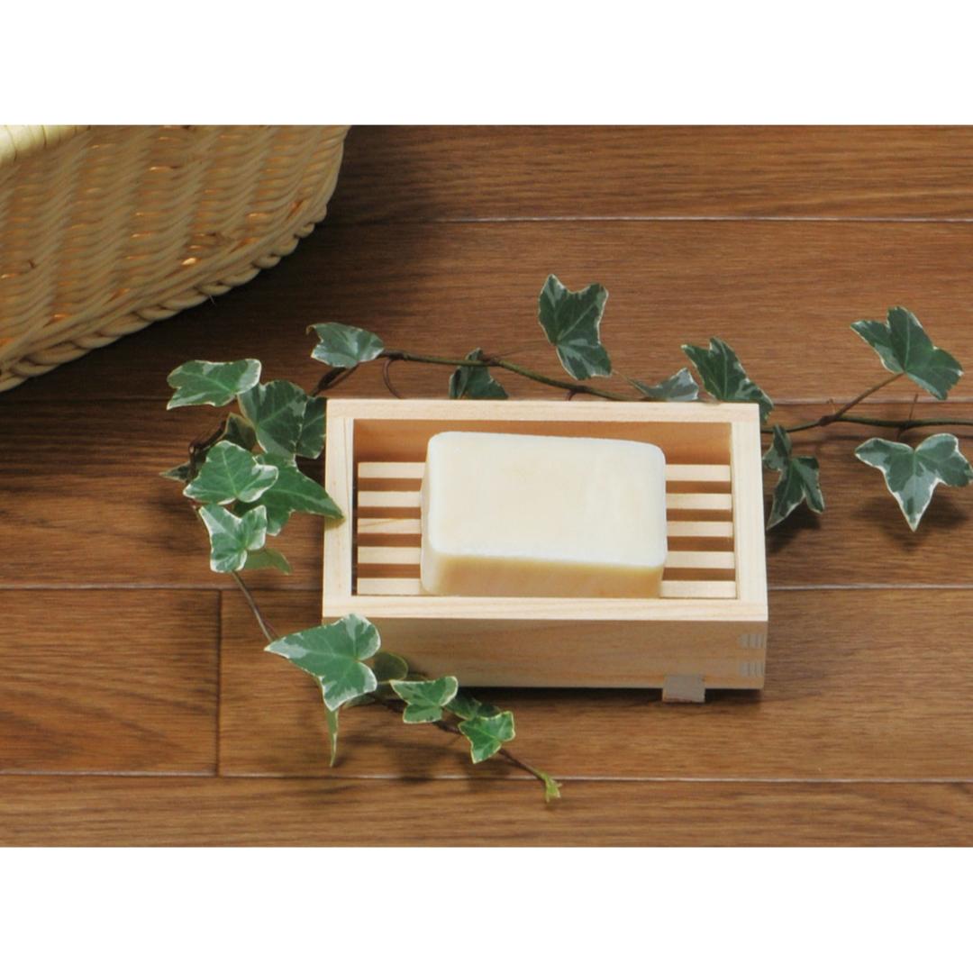 Bar of soap on wooden dish with ivy on a table.