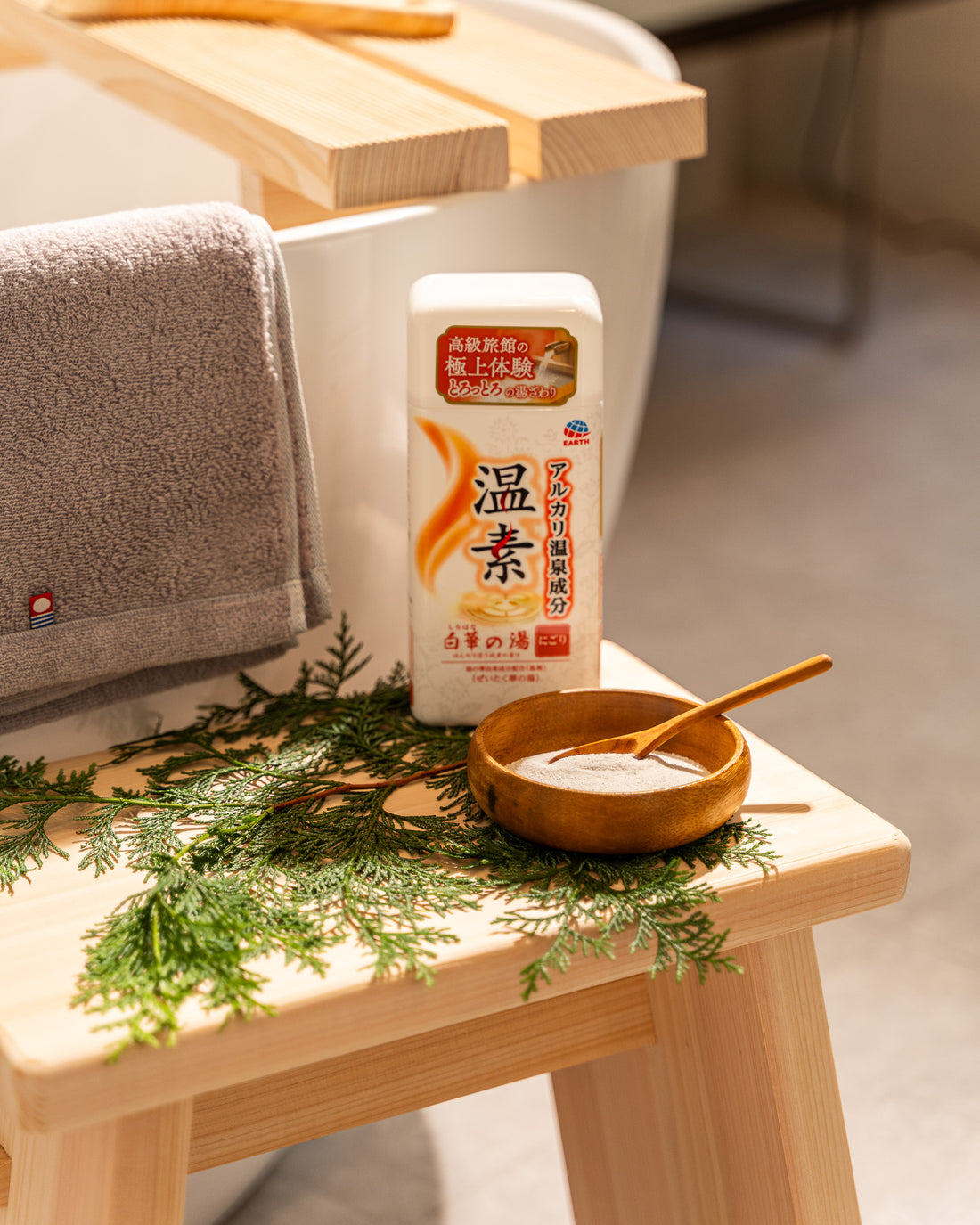 Bottle of Japanese body lotion on a wooden stool with a bowl and green leaves