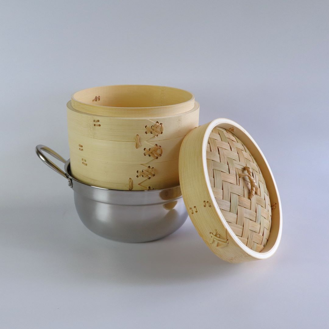 Bamboo seiro steam basket stacked on a stainless steel pot, featuring a two-tier design and a woven bamboo lid.