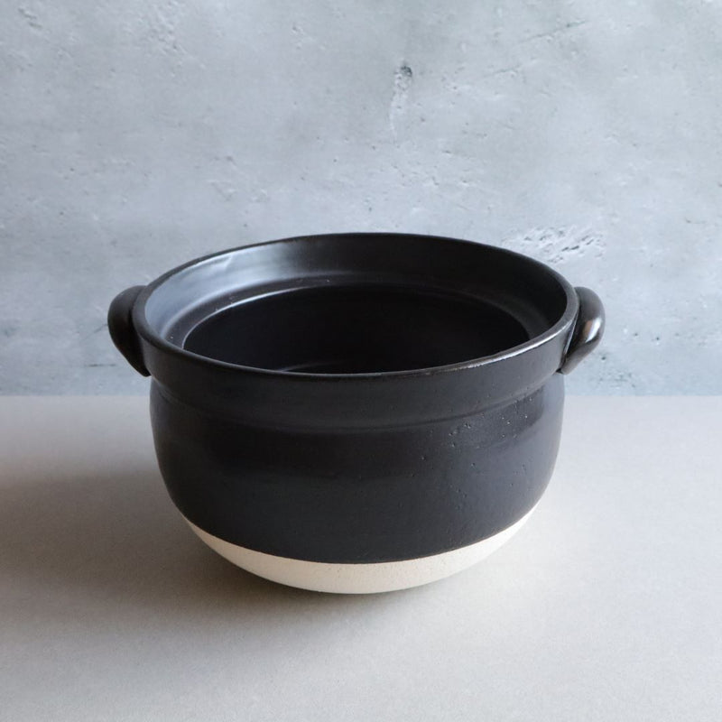 A black glazed donabe rice cooker without the lid, showcasing the spacious interior. The cooker is made from high-quality ceramic, ideal for even heat distribution.