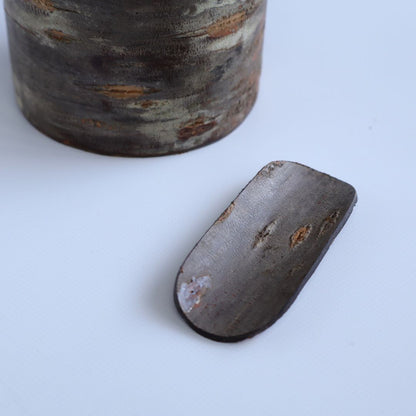 A close-up of a handmade tea scoop crafted from cherry bark, showing its natural texture and detailed craftsmanship.