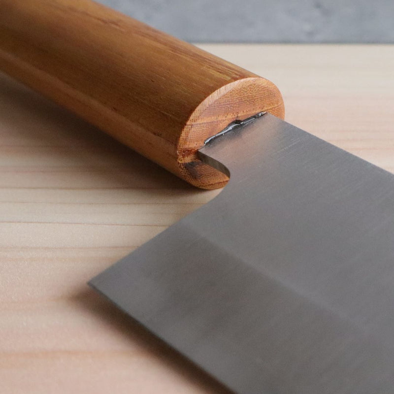 A close-up view of the base of a Japanese knife with a brown wooden handle, showing the intricate join between the blade and the handle.