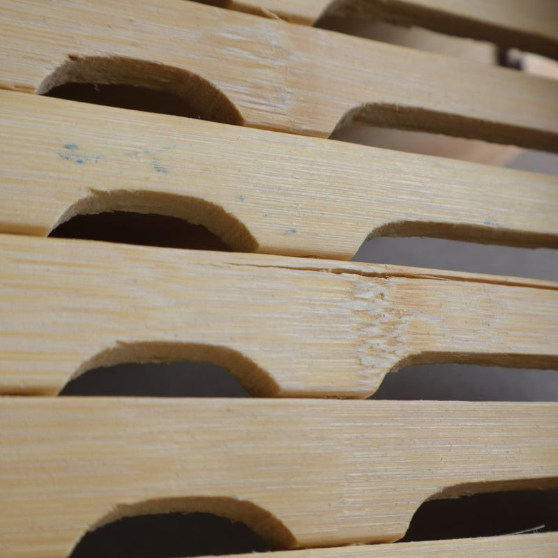 Close-up of the ventilation slots on the bottom of a Japanese bamboo steamer basket, showcasing the natural bamboo texture.