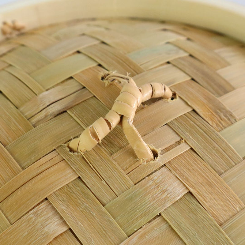 Close-up of the woven bamboo lid of a seiro steam basket, showing the rattan handle attached to the top.