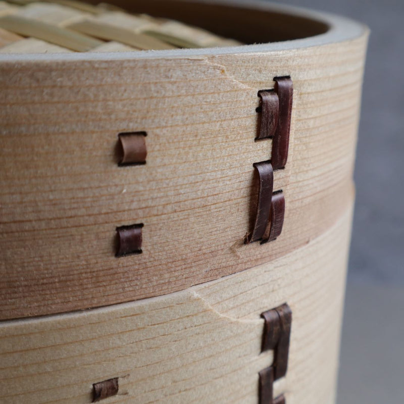 Detailed view of the wooden sides of a Japanese steamer basket, highlighting the precise craftsmanship and dark lacing.