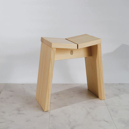Wooden stool on a light-colored floor with a plain background