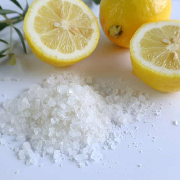 Close-up of bath salt crystals next to fresh lemon halves, emphasizing the natural and refreshing ingredients used in the Setouchi Lemon Bath Salt.