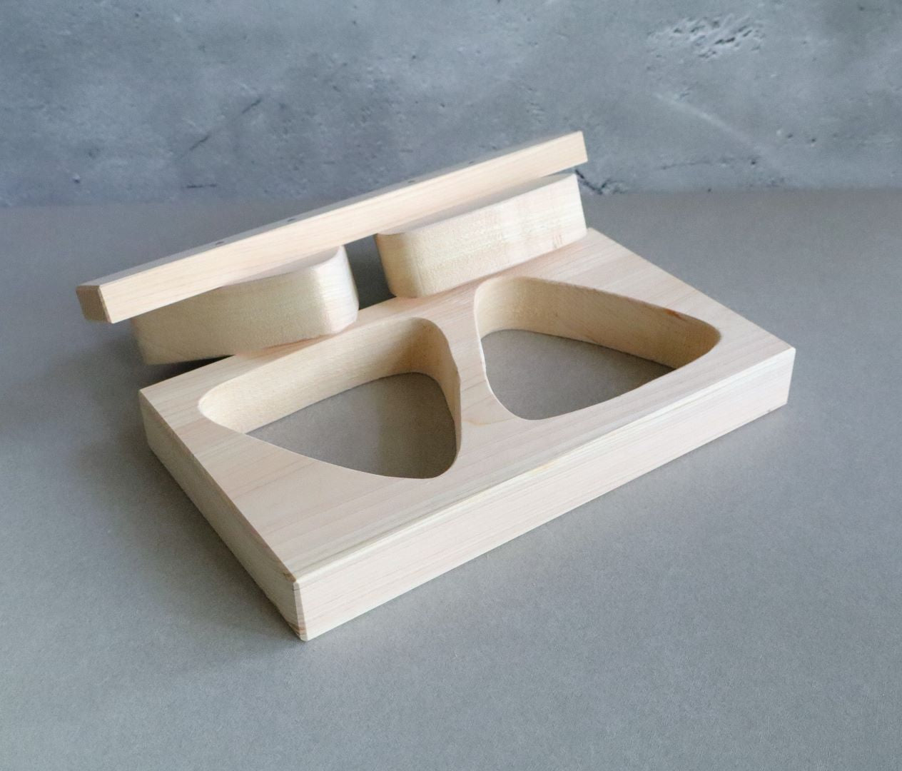 Side view of a handmade Hinoki wood onigiri mold with two triangular shapes and an attached wooden press.