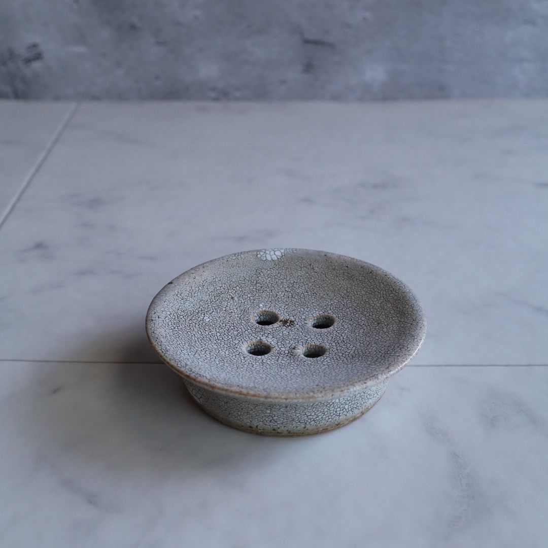 Top-down view of a handmade Japanese ceramic soap dish with four drainage holes and a crackled kairagi glaze finish