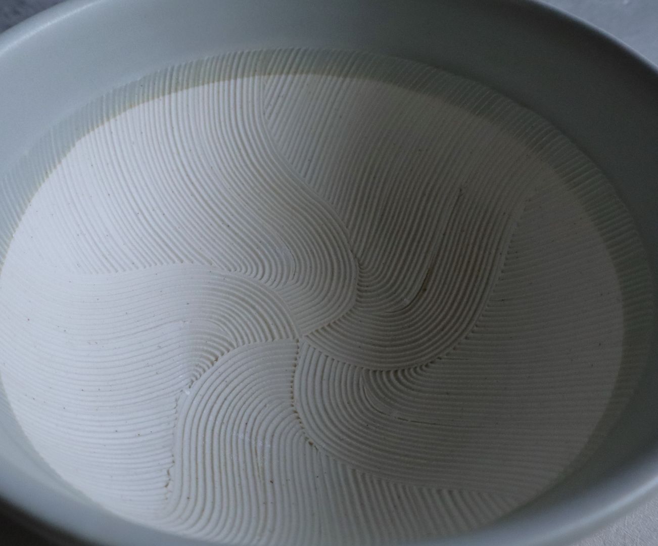 Close-up view of the finely grooved interior pattern of a ceramic suribachi grinding bowl.