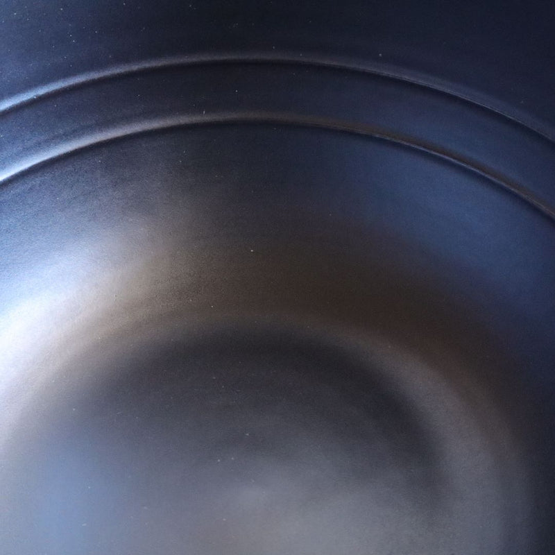 Close-up view of the interior of a black glazed donabe rice cooker, displaying the smooth, high-quality ceramic finish that ensures even cooking.