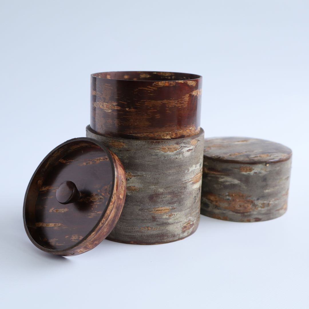 A traditional Japanese tea caddy made from polished cherry bark, showcasing its removable lid and elegant, natural texture.