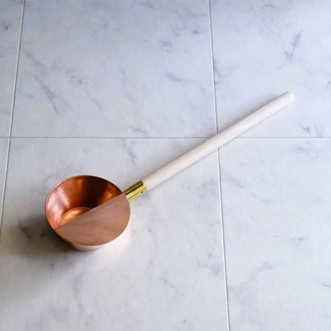Handcrafted Japanese copper sauna ladle with a long beechwood handle, designed for authentic sauna rituals.