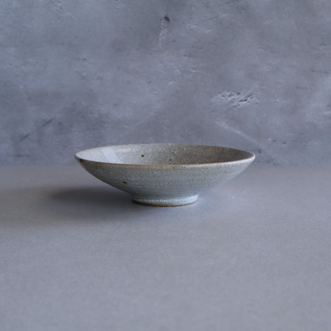 Side view of the handmade ceramic plate, showing its gently flared rim and slightly elevated foot.